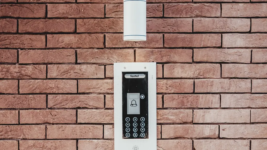 Keypad and intercom entry panel mounted on a brick wall