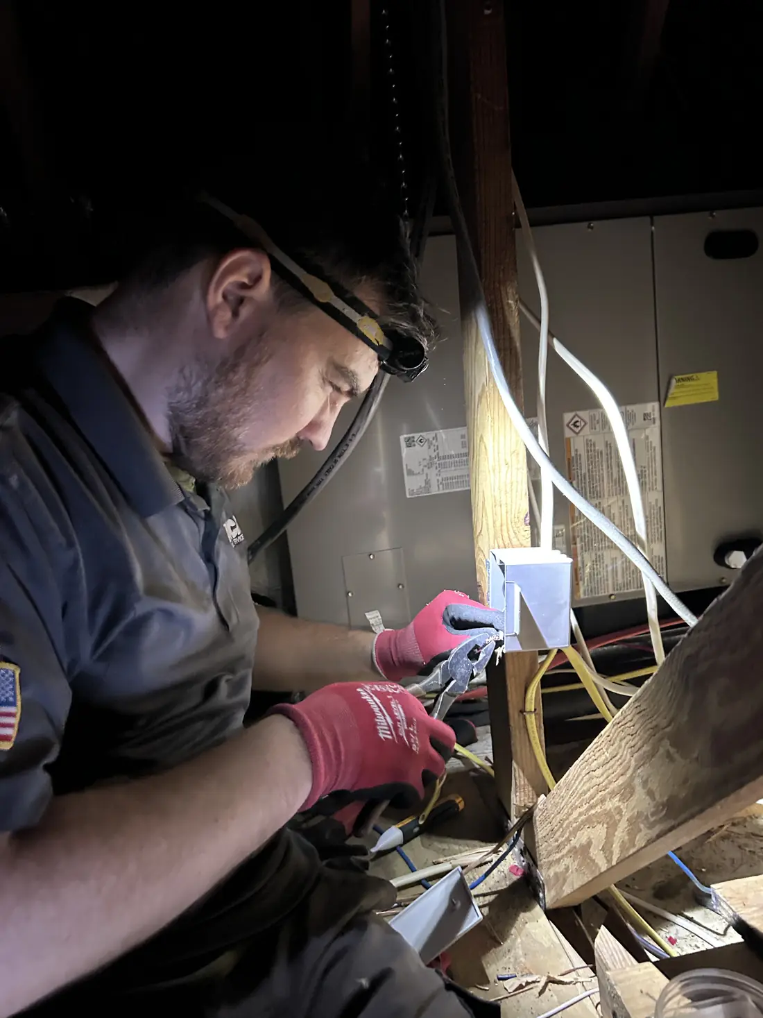 Kincaid Electric electrician in work gloves repairing wiring in a ceiling space