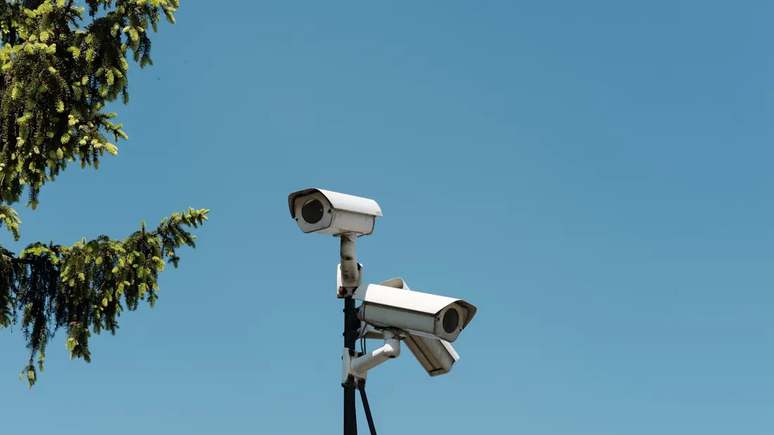 Security cameras mounted on a pole against a blue sky